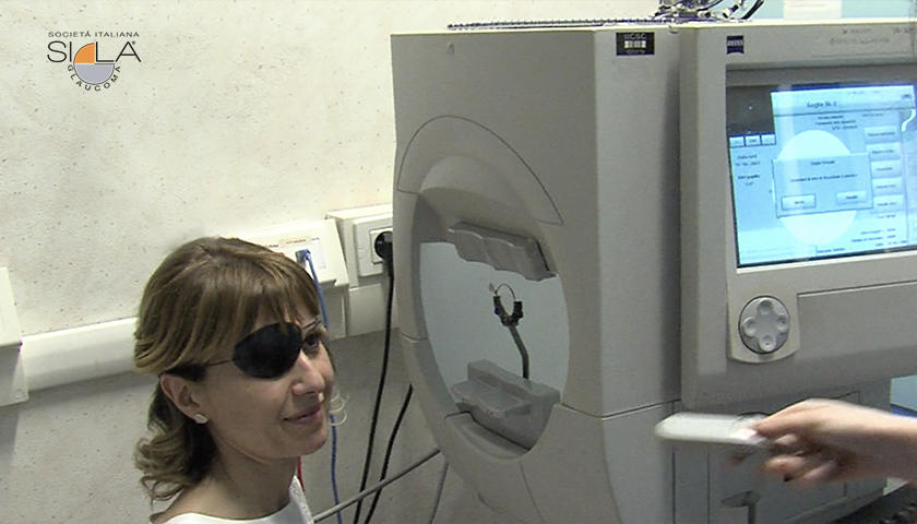 Donna con benda vicino al macchinario che esegue l'esame del campo visivo
